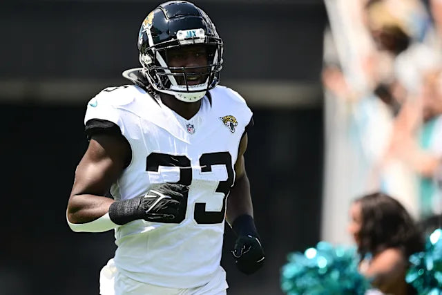 Football player in a white jersey with number 23 and helmet, running on a field.